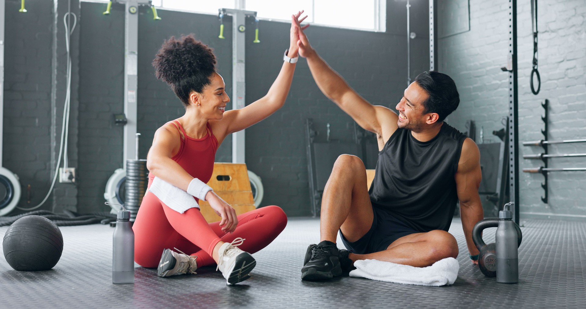 Woman, man and high five for fitness, gym partnership and happy for growth, development or health on floor. Personal trainer, girl and success with smile, congratulations or motivation for mentorship